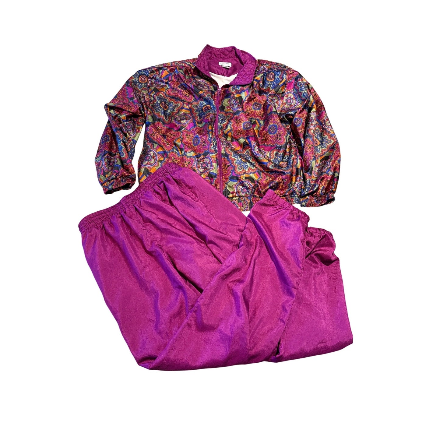A two-piece tracksuit set featuring a long-sleeve zip-up jacket with a vibrant multicolor paisley pattern and matching solid magenta pants, laid flat on a white background.