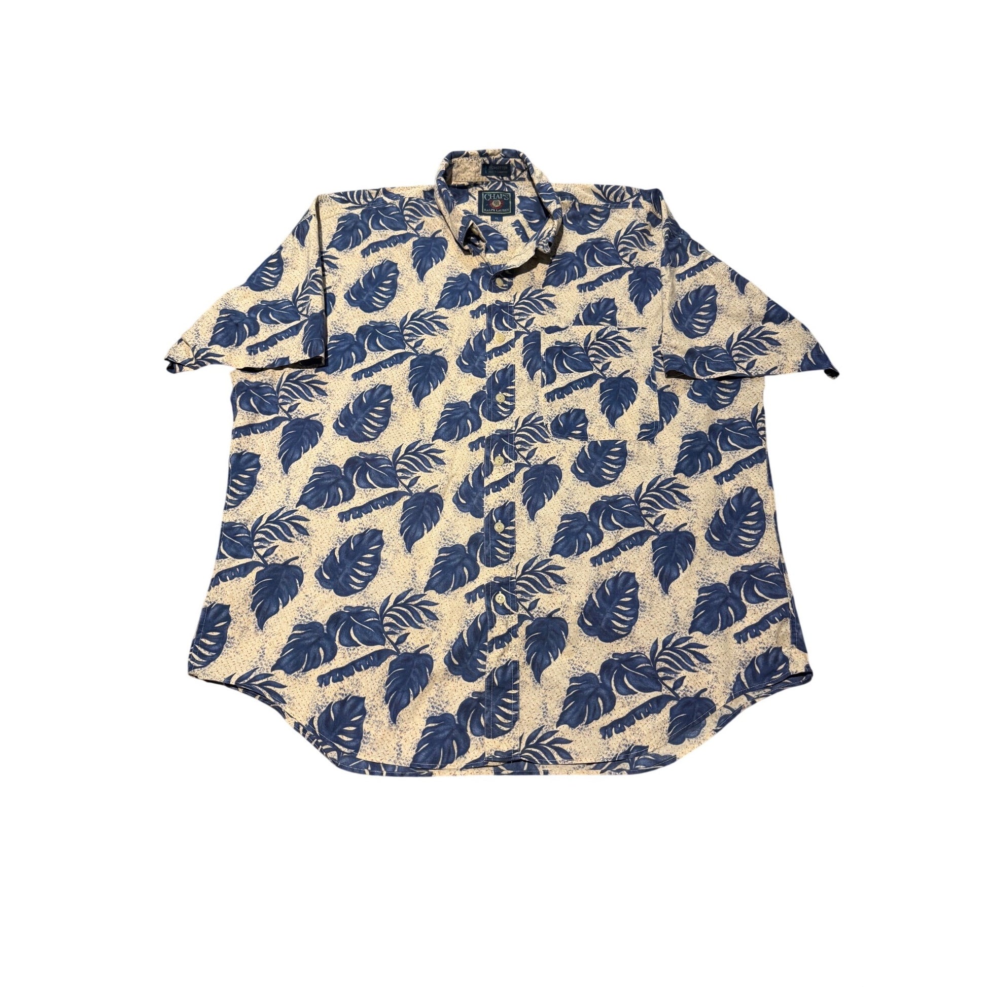 A short-sleeve button-up shirt with a beige base and a dark blue tropical leaf pattern, laid flat against a white background.