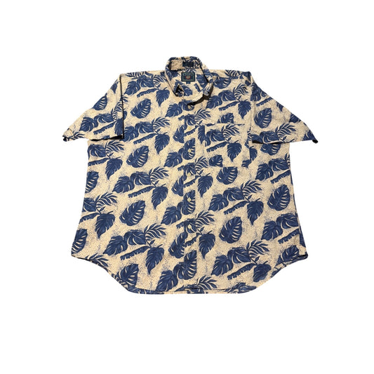 A short-sleeve button-up shirt with a beige base and a dark blue tropical leaf pattern, laid flat against a white background.