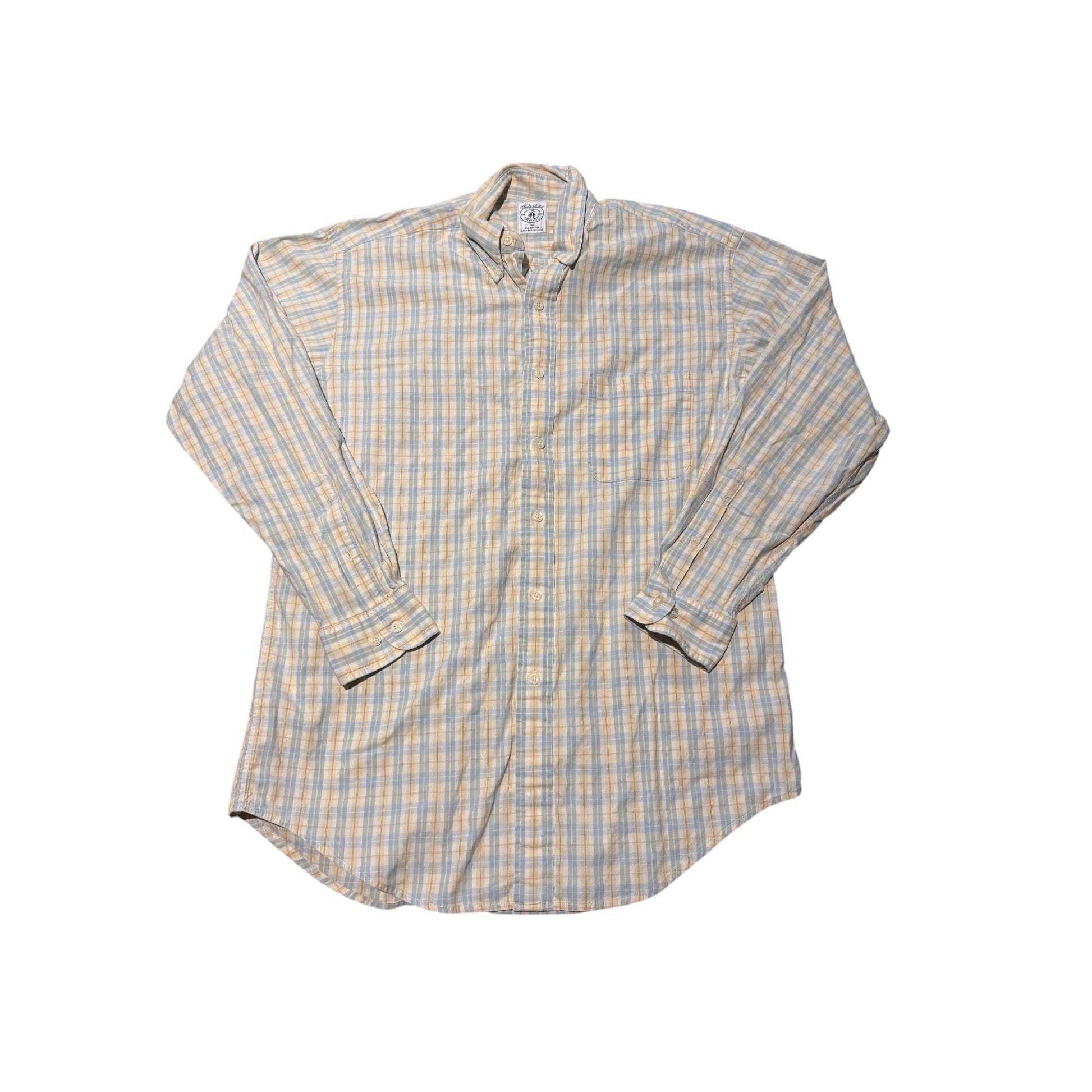 A long-sleeve button-down shirt with a beige, white, and light blue plaid pattern, laid flat against a white background.