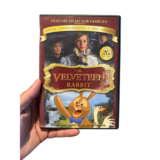 A hand holding a DVD case for 'The Velveteen Rabbit' 2-disc commemorative edition, shown against a plain white background.
